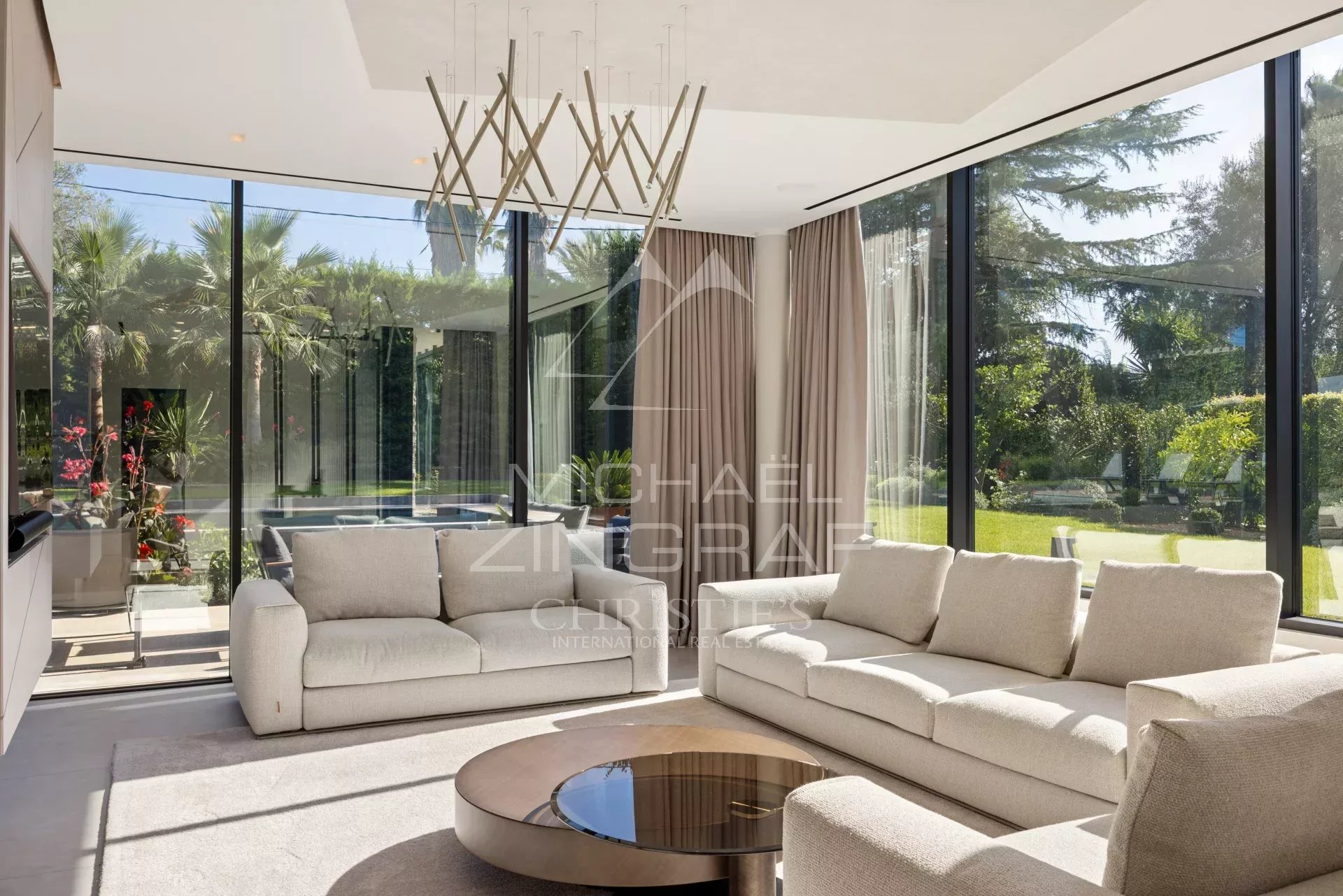 Intérieur d'une villa contemporaine à Cap d'Antibes, salon lumineux avec grandes baies vitrées et mobilier moderne.