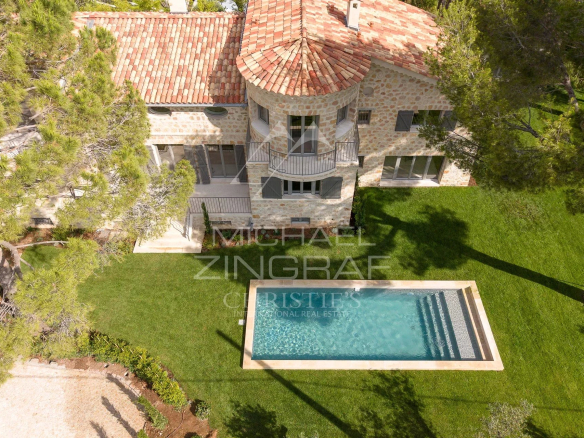Vue aérienne d'une villa en pierre avec piscine, entourée d'arbres au Cap d'Antibes.