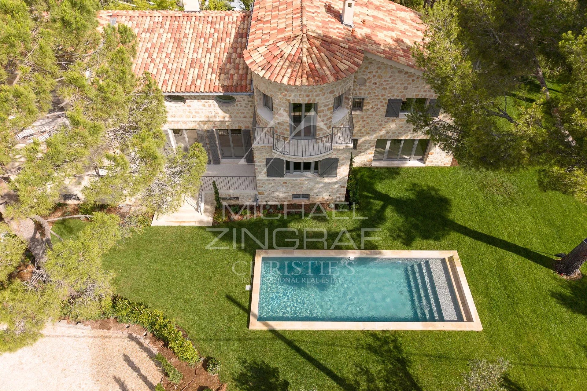 Villa de luxe au Cap d’Antibes Vue aérienne d'une villa en pierre avec piscine, entourée d'arbres au Cap d'Antibes.