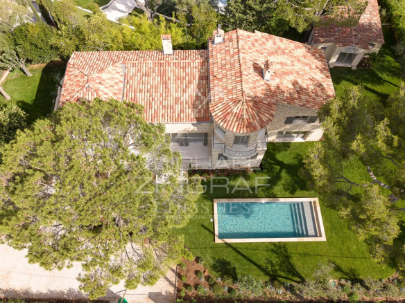 Vue aérienne d'une villa en pierre avec piscine à Cap d'Antibes, entourée d'arbres.