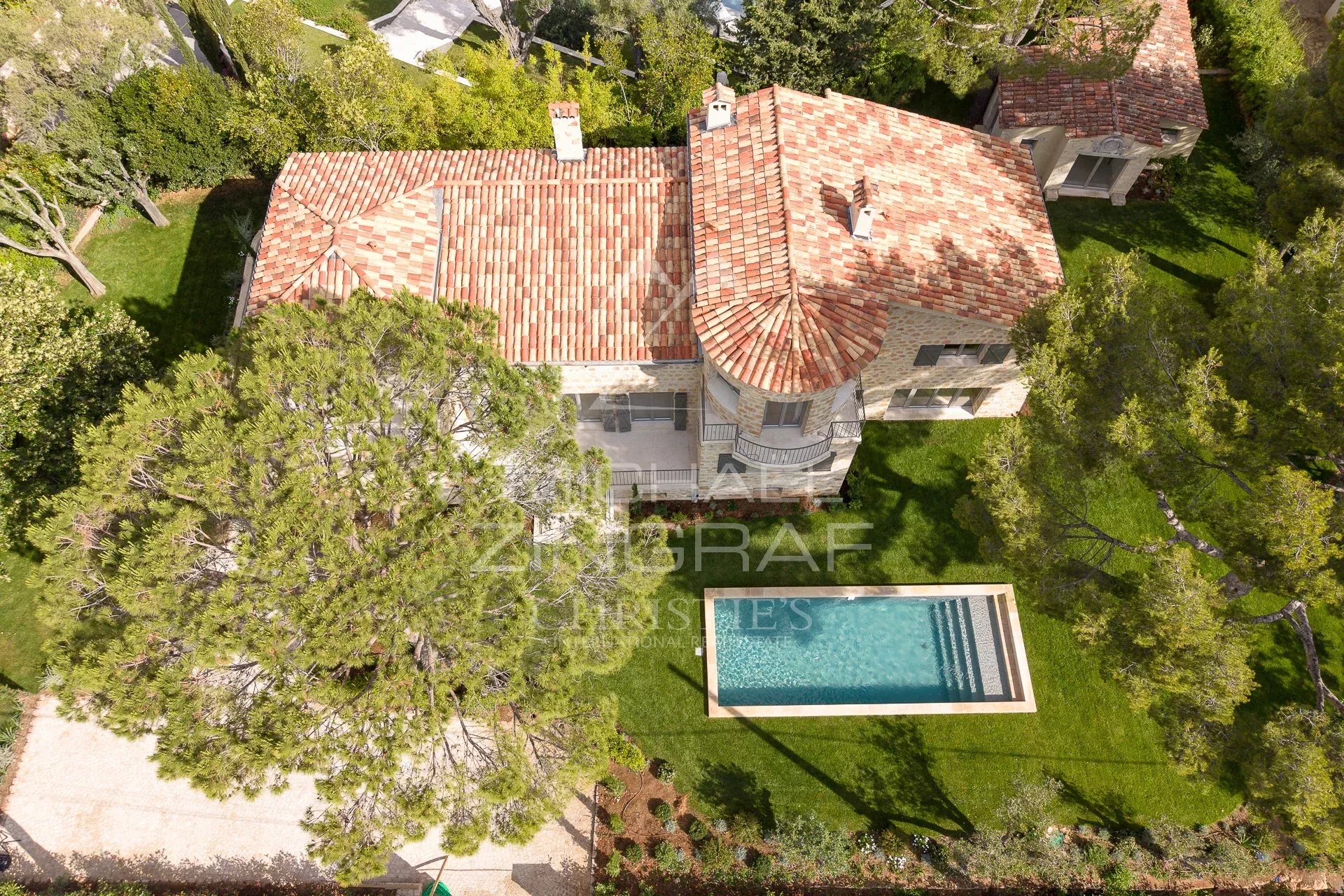 Villa de luxe à Cap d’Antibes Vue aérienne d'une villa en pierre avec piscine à Cap d'Antibes, entourée d'arbres.