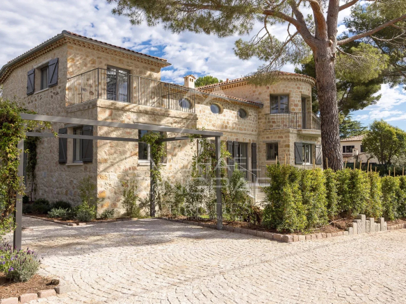 Villa en pierre rénovée avec jardin au Cap d’Antibes, entourée de verdure.