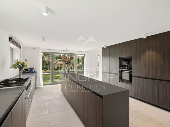 Cuisine moderne avec îlot central et grandes baies vitrées donnant sur le jardin.