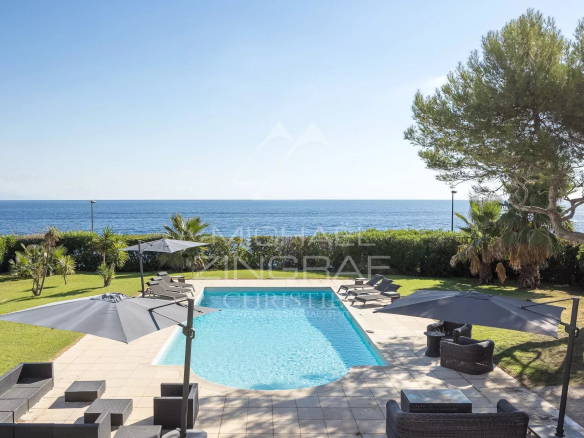View of the pool and garden of the villa in Cap d'Antibes with the sea in the background.