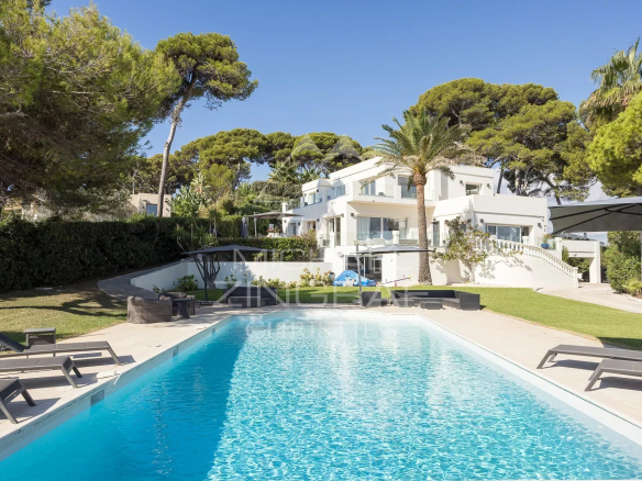 Modern villa with swimming pool in Cap d'Antibes, surrounded by trees and outdoor spaces.