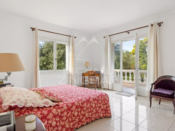 Spacious room with bed and windows opening onto a balcony, decorated with flowers.