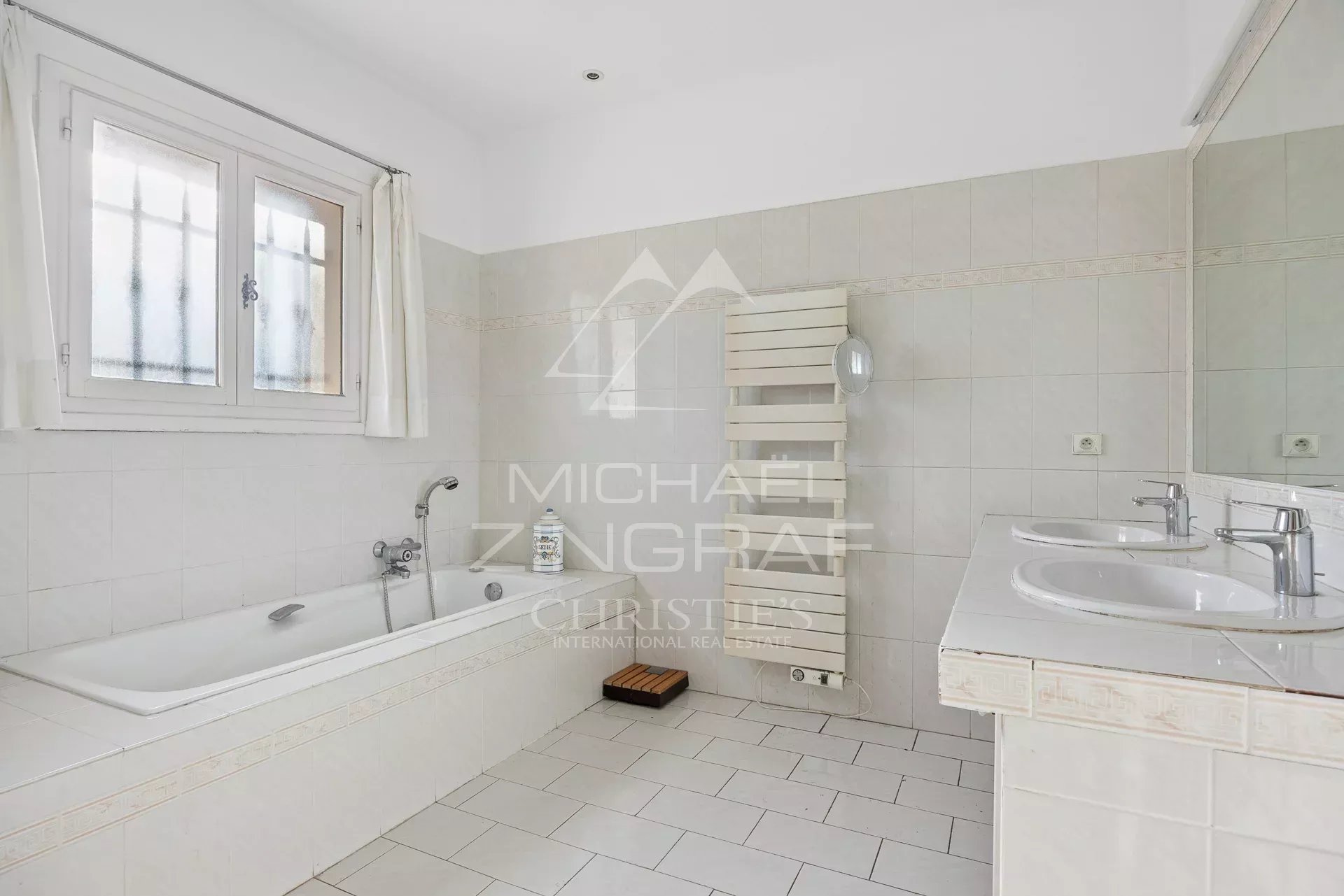 Bathroom in a property in Antibes Spacious bathroom with bathtub and double sink in a house in Antibes.