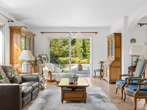 Bright living room with views of the garden and pool, wooden furniture and comfortable sofas.