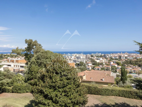 Vue panoramique sur la mer et la ville d'Antibes depuis un espace vert.