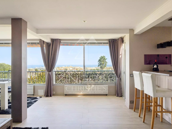 Intérieur d'un appartement à Antibes avec vue mer, salon lumineux et espace bar.