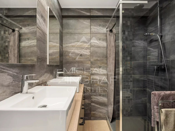 Salle de bain moderne avec douche et deux lavabos, carrelage gris