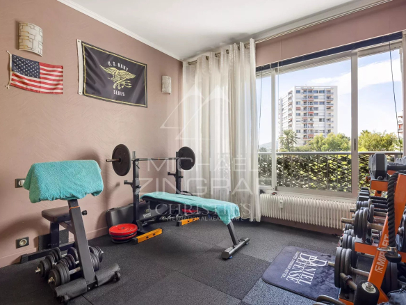 Salle de sport avec équipements de fitness, fenêtres ouvertes sur un balcon à Antibes.