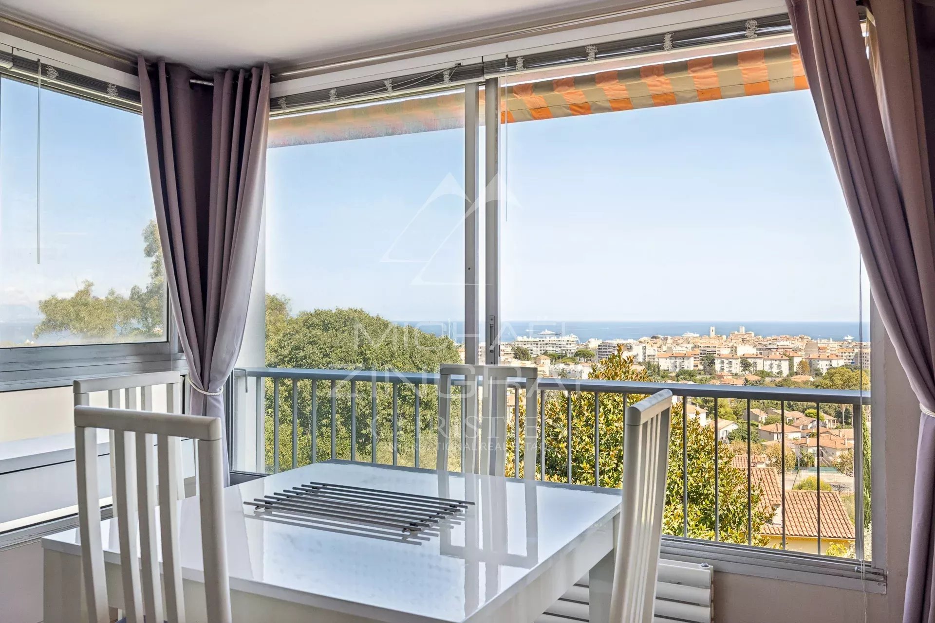 Appartement avec vue panoramique à Antibes Vue depuis un appartement à Antibes avec une table et des chaises, offrant une vue panoramique sur la mer et la ville.