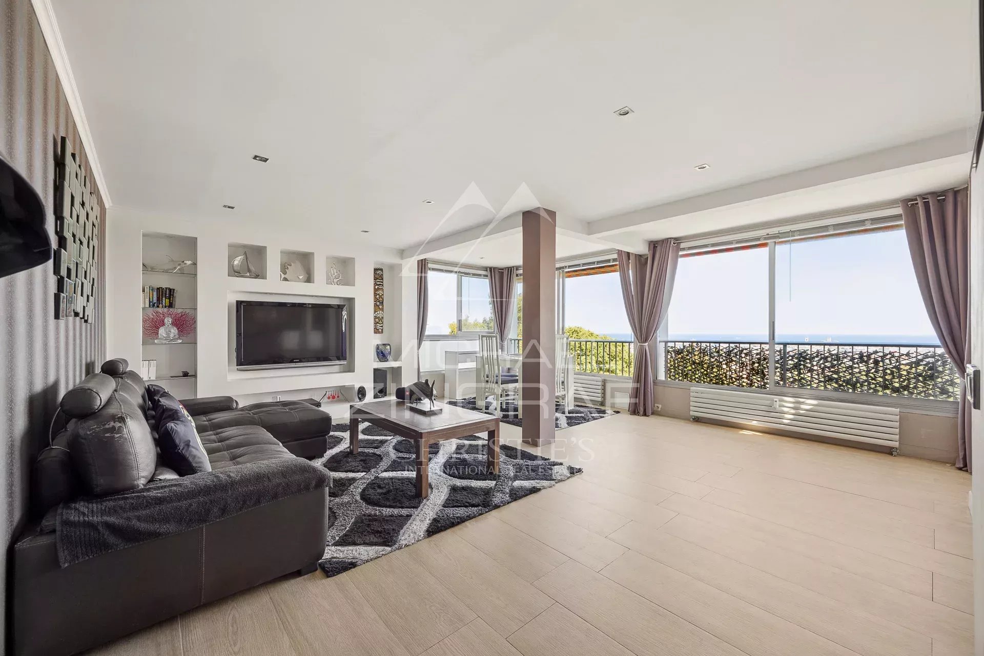 Salon d’un appartement à Antibes Salon spacieux d'un appartement à Antibes avec vue mer et accès à un balcon.