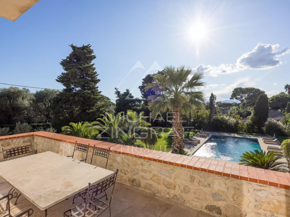 Vue sur la piscine et le jardin d'une villa moderne à Antibes sous un ciel ensoleillé.