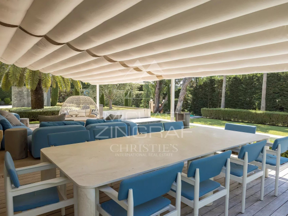 Terrasse d'une villa néo-provençale avec mobilier moderne et jardin verdoyant au Cap d'Antibes.