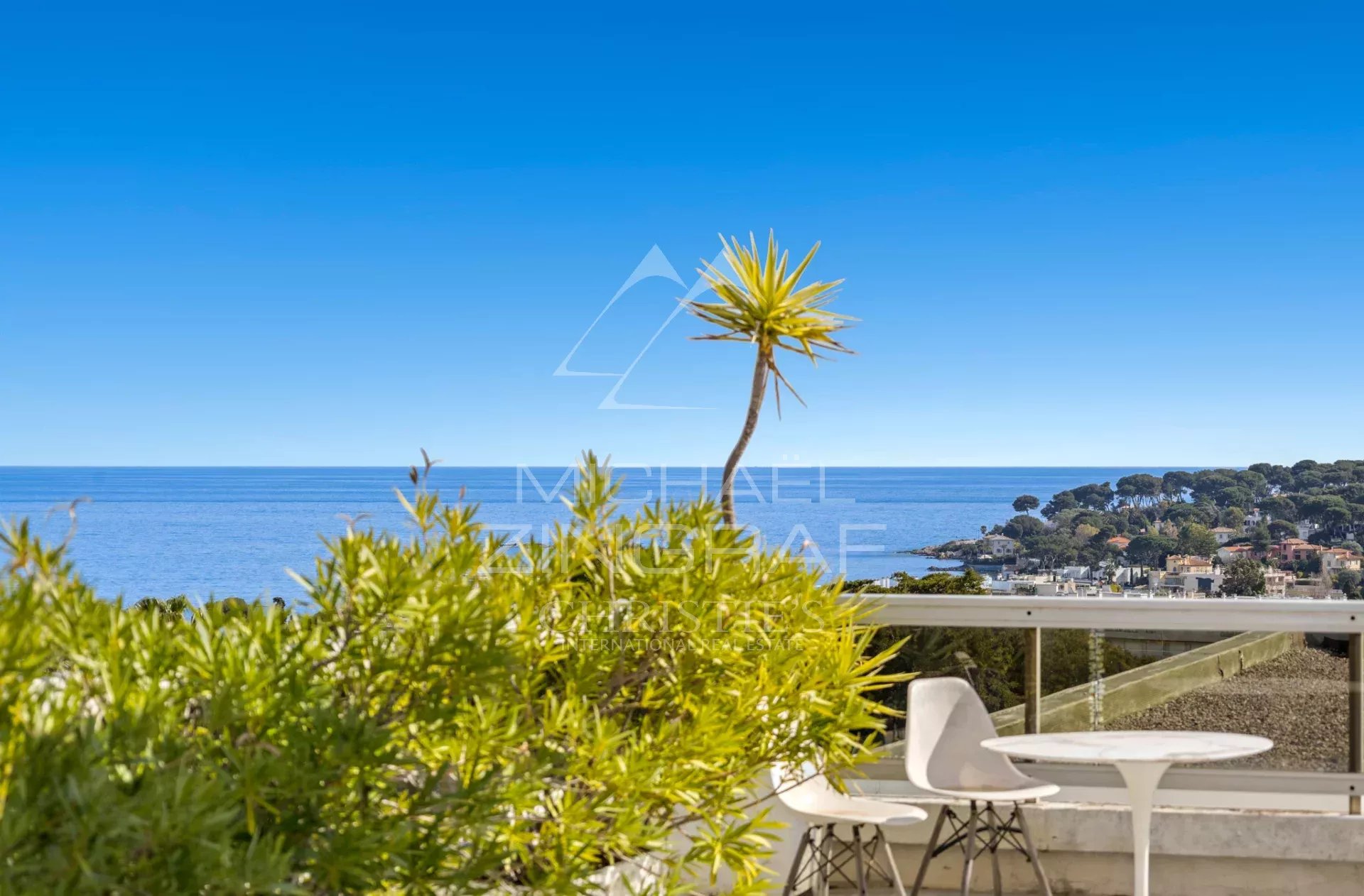 Villa sur le toit avec vue mer à Antibes Vue panoramique depuis une villa sur le toit à Antibes, avec mer et végétation en premier plan.
