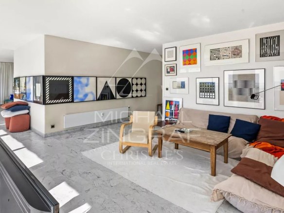 Intérieur d'une villa sur le toit avec salon lumineux et œuvres d'art, vue sur la mer.