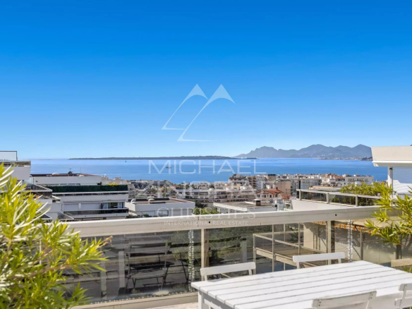 Vue panoramique depuis une villa sur le toit à Antibes, avec mer et montagnes en arrière-plan.