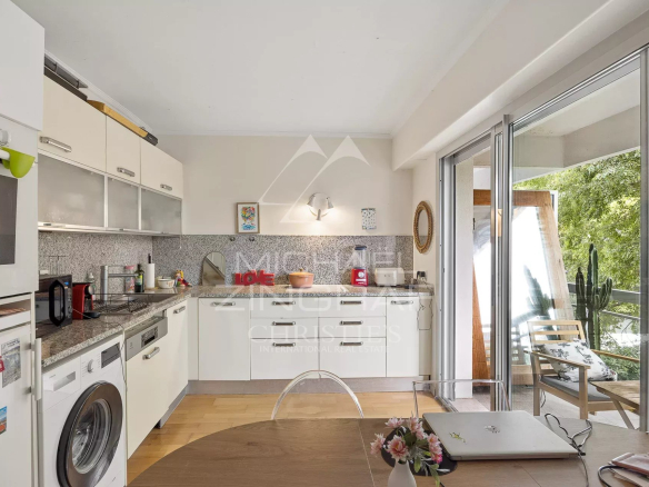 Cuisine moderne et lumineuse d'un appartement à Cap d'Antibes avec vue sur un parc arboré.