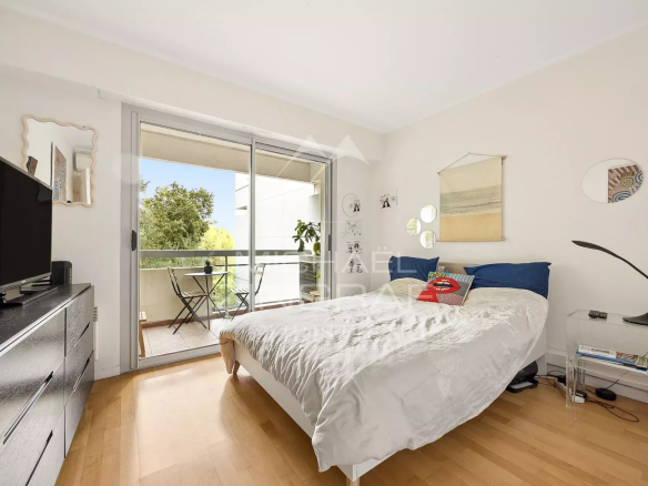 Chambre d'un appartement au Cap d'Antibes avec balcon et vue sur un parc arboré.