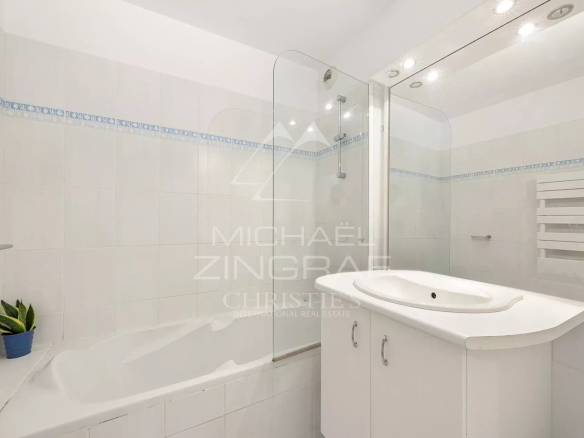 Salle de bain moderne avec baignoire et douche, carrelage clair.