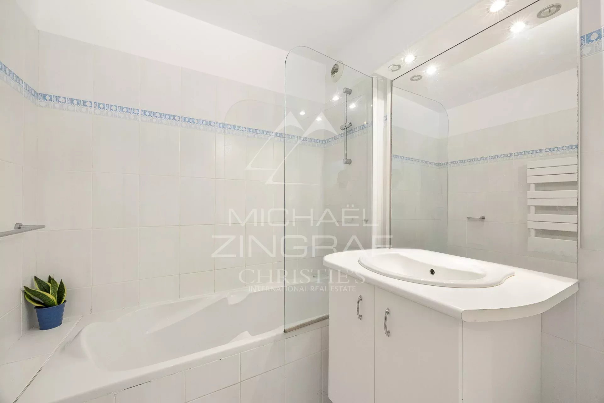 Salle de bain moderne avec baignoire et douche, carrelage clair.