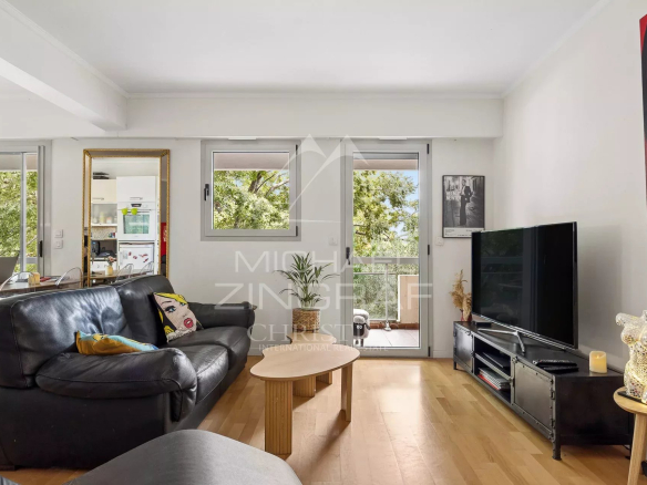 Salon d'un appartement à Cap d'Antibes avec canapé et télévision, donnant sur un balcon.