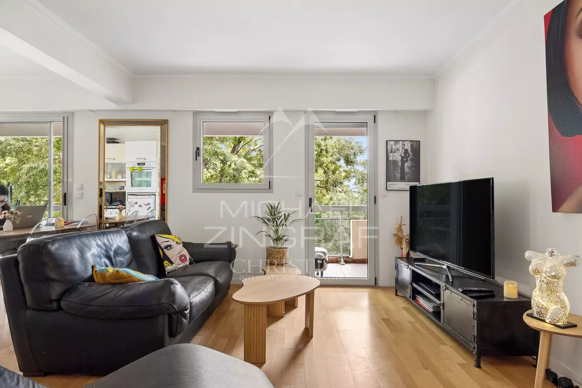 Salon d'un appartement à Cap d'Antibes avec canapé et télévision, donnant sur un balcon.