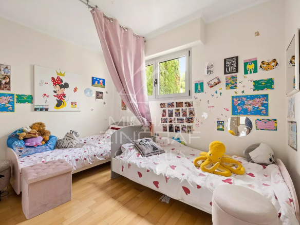 Chambre d'enfants avec lits jumeaux et décorations murales colorées.