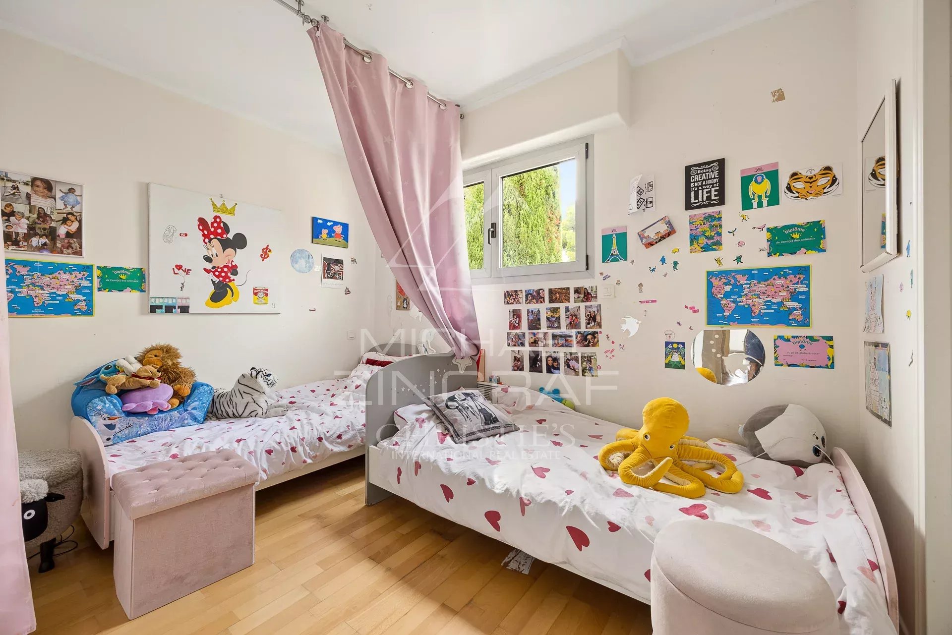 Chambre d'enfants avec lits jumeaux et décorations murales colorées.