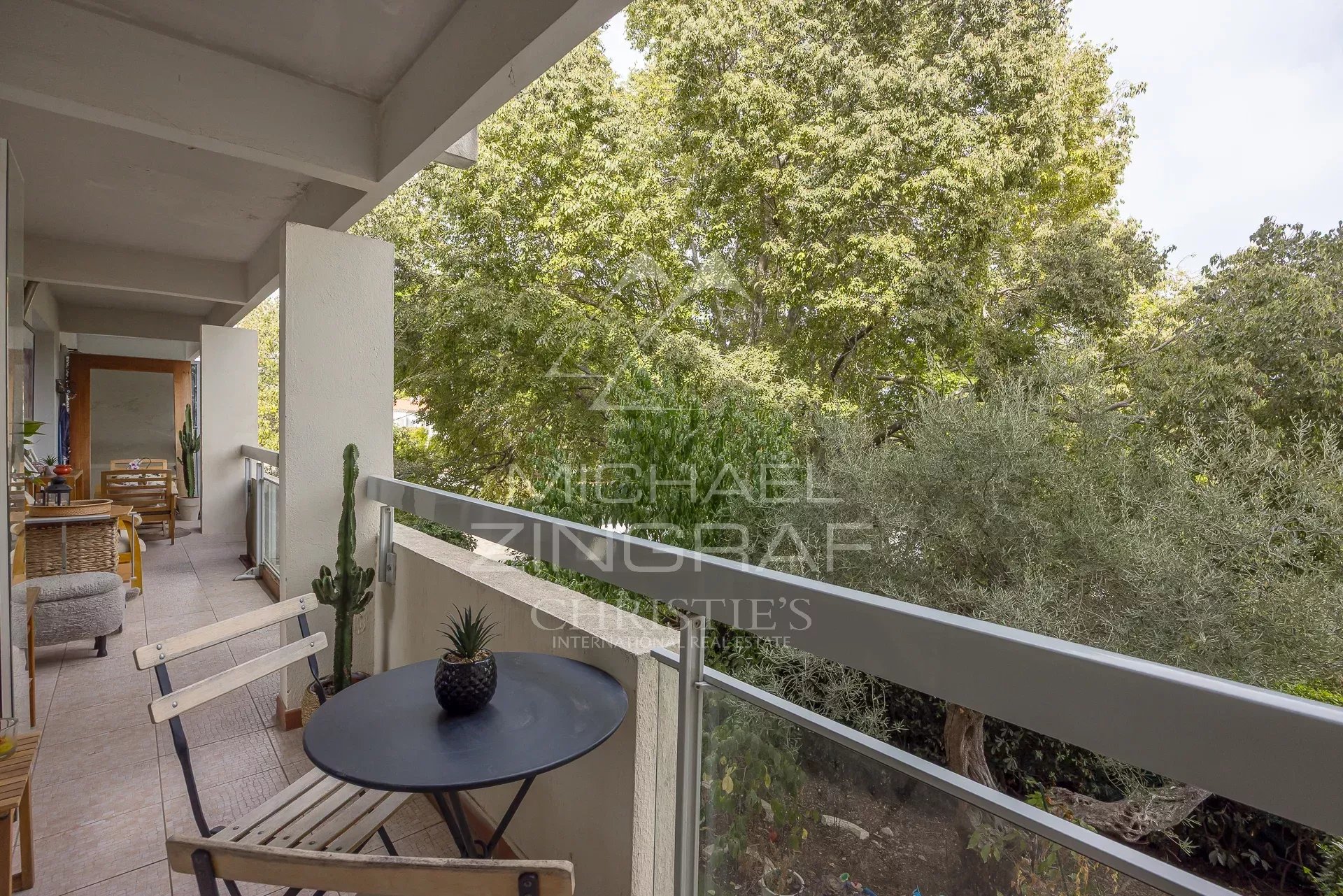 Balcon d'un appartement au Cap d'Antibes avec vue sur un parc arboré.