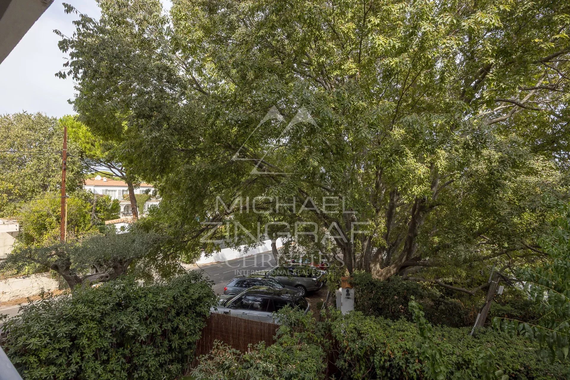 Vue depuis un appartement à Cap d'Antibes, avec des arbres et des voitures visibles.