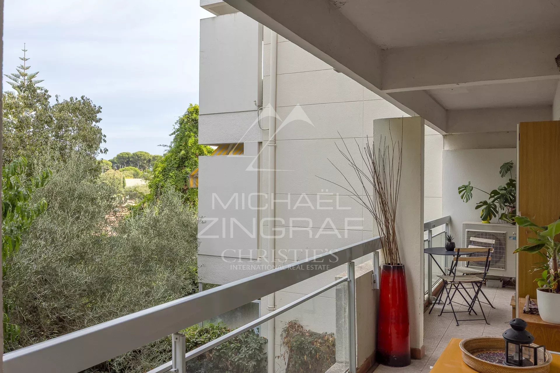Balcon d'un appartement au Cap d'Antibes avec vue sur un parc arboré.