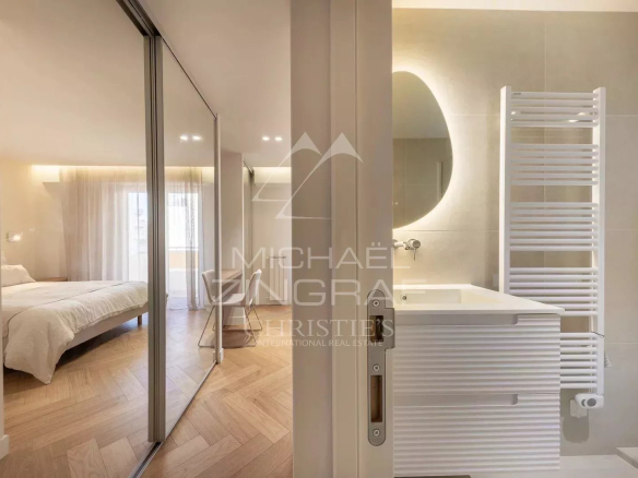 Modern bathroom with sink and mirror, overlooking a bedroom