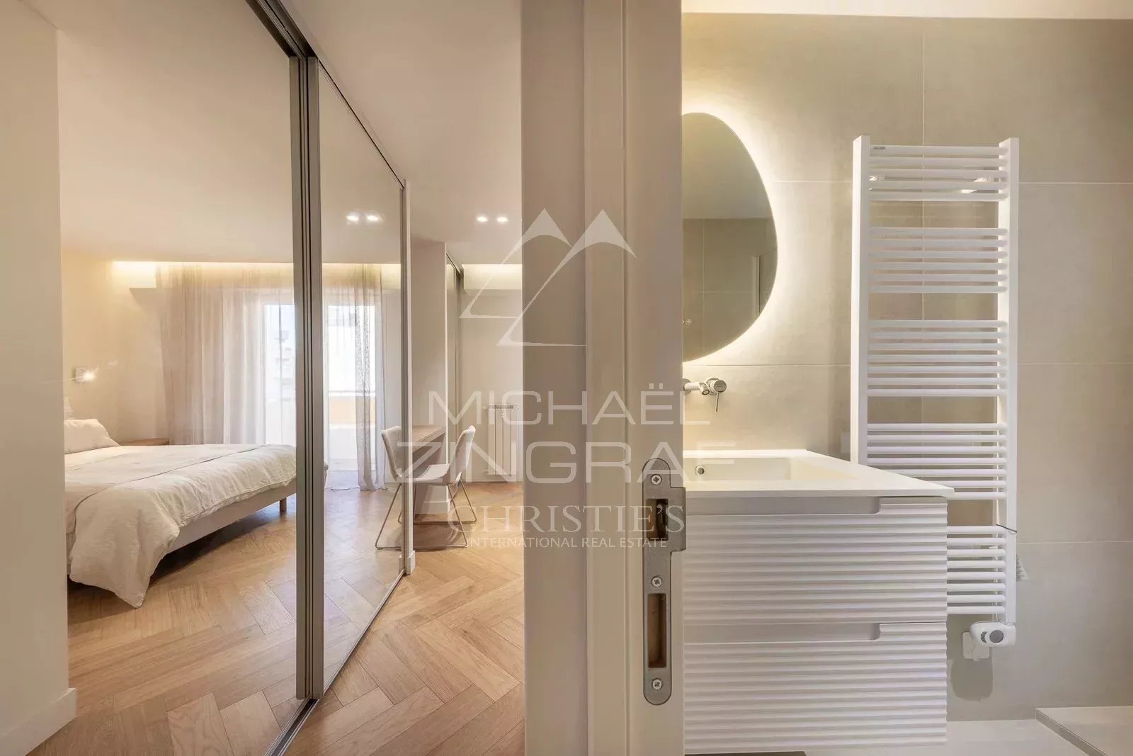 Modern bathroom with sink and mirror, overlooking a bedroom