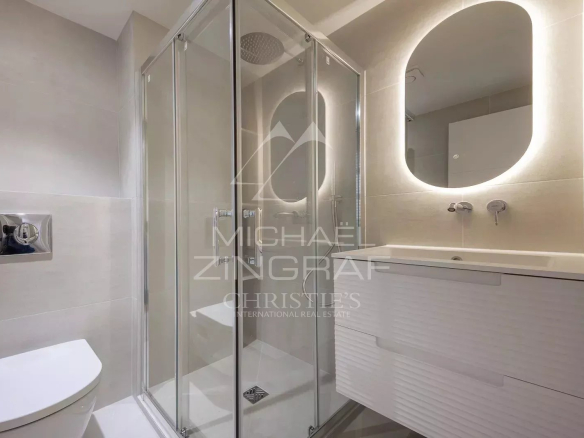Modern bathroom with glass shower and vanity unit, LED lighting.