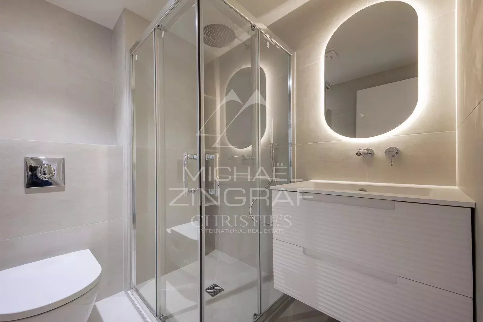 Modern bathroom with glass shower and vanity unit, LED lighting.