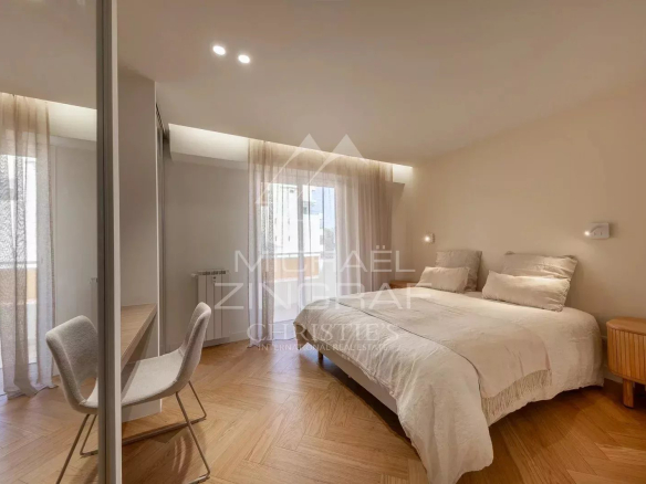 Bright room with double bed and desk, windows with light curtains.