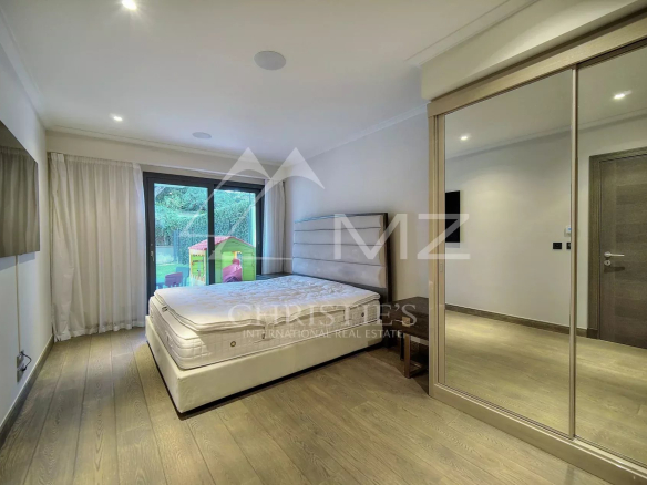 Chambre d'un appartement à vendre au Parc du Cap à Antibes, avec lit et accès à un jardin.