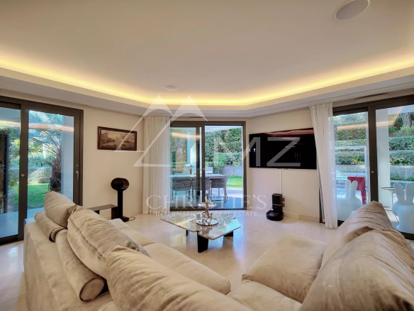 Intérieur d'un appartement moderne avec un salon lumineux et accès à un jardin.