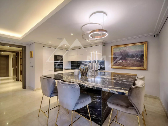 Cuisine moderne d'un appartement luxueux avec un îlot central et des chaises autour.