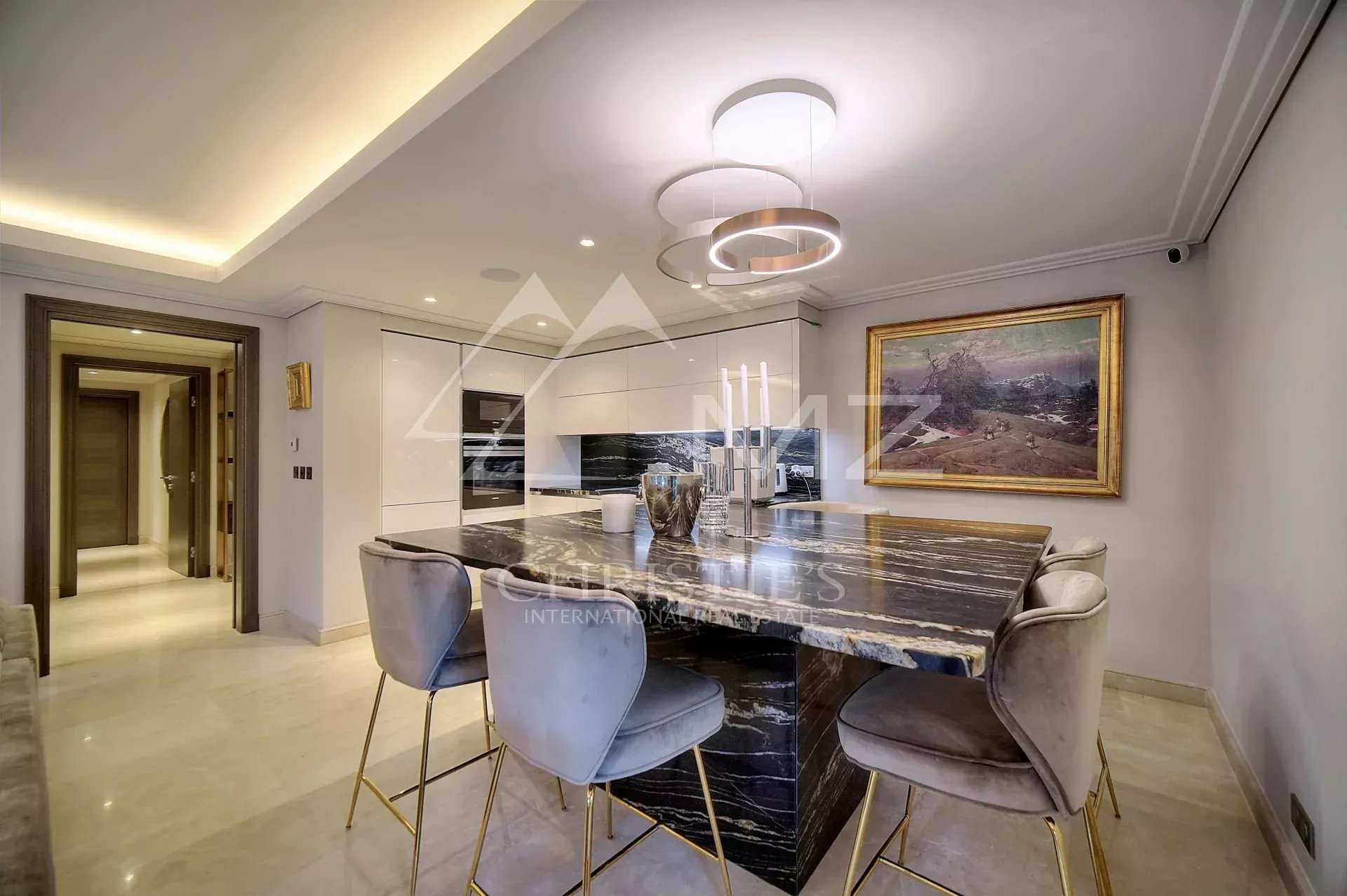 Appartement de luxe à Antibes Cuisine moderne d'un appartement luxueux avec un îlot central et des chaises autour.