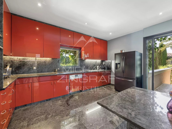 Modern kitchen with red cabinets and a marble worktop in a contemporary villa in Antibes.