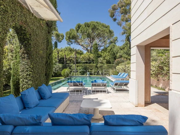 Terrace of a contemporary villa with swimming pool and sun loungers, surrounded by greenery in Antibes.