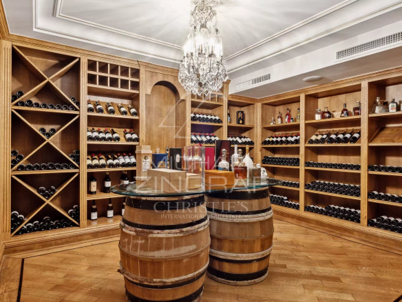 Wooden wine cellar with bottles, decorated with a chandelier, in a Belle Époque style property in Antibes.