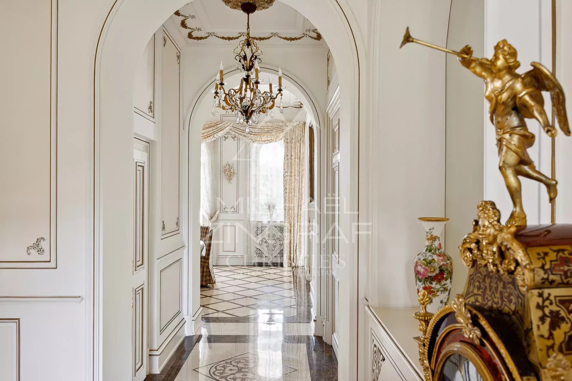 Interior of a Belle Époque style property with a decorated hallway and a chandelier.