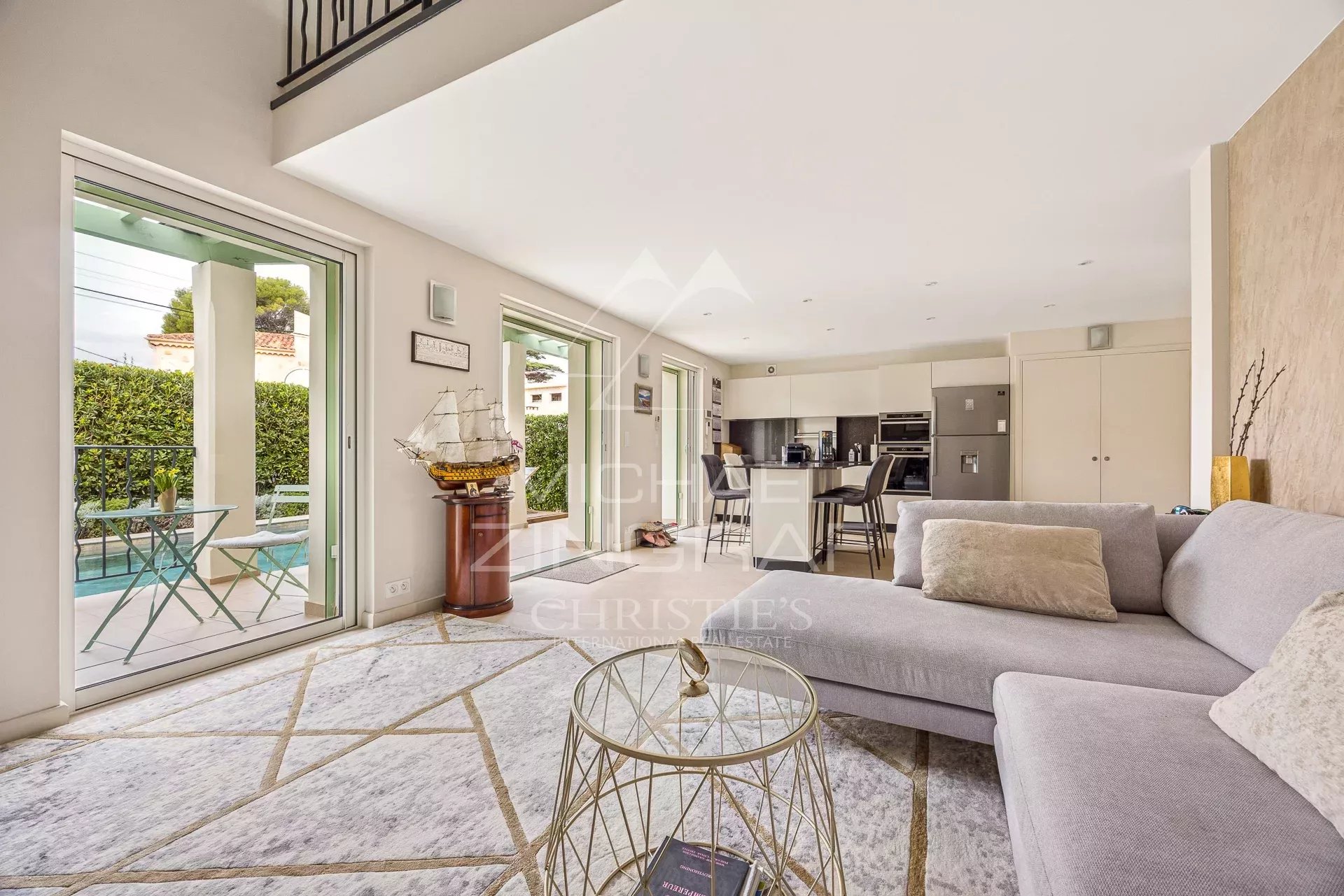 Intérieur d'une maison rénovée avec salon lumineux, cuisine moderne et accès à l'extérieur.