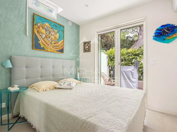 Chambre lumineuse avec lit double et accès à un jardin, décorée de manière moderne.