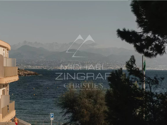 Vue sur la mer depuis le Cap d'Antibes, avec des montagnes en arrière-plan.